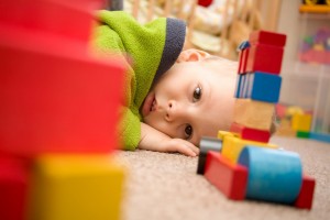 Sick boy is among the toys on the floor.